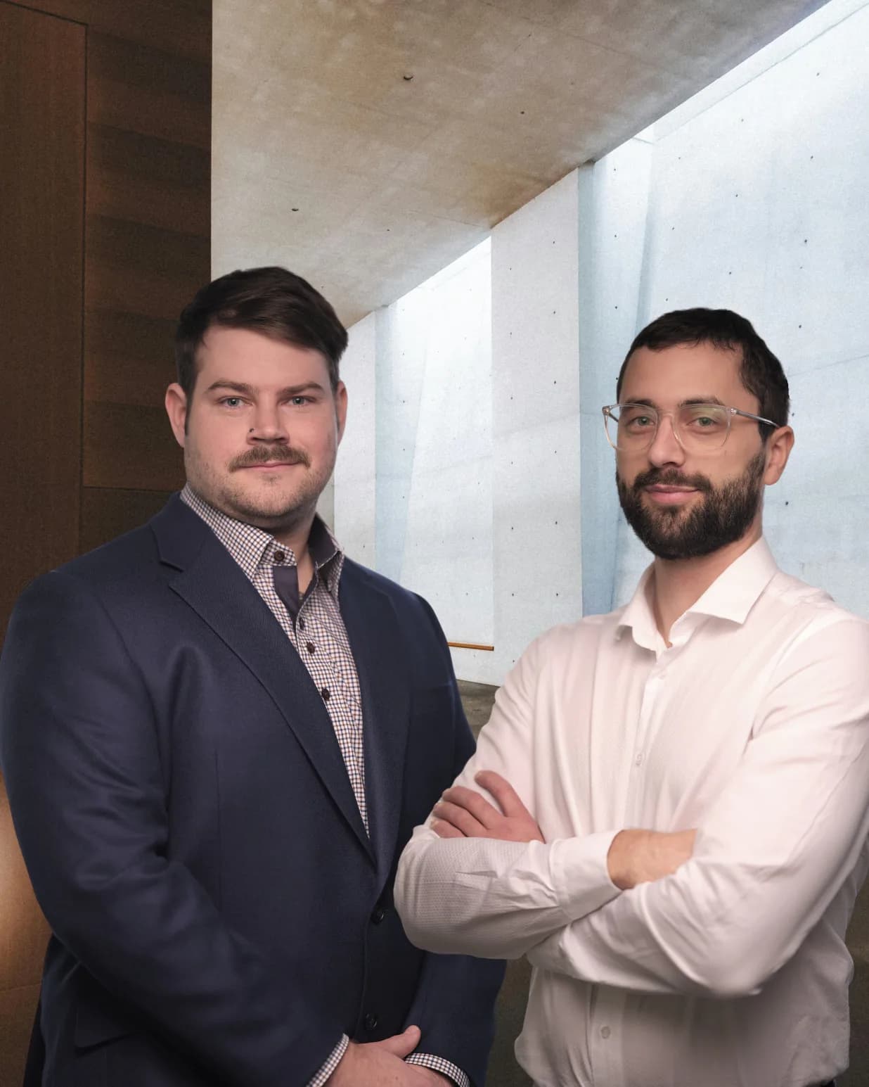 Les deux fondateurs de SIMPLE Services-Conseils, bras croisés, devant un mur de béton